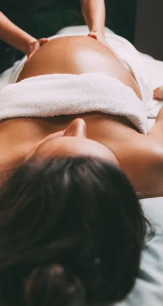 Photo de mains qui massent une femme enceinte